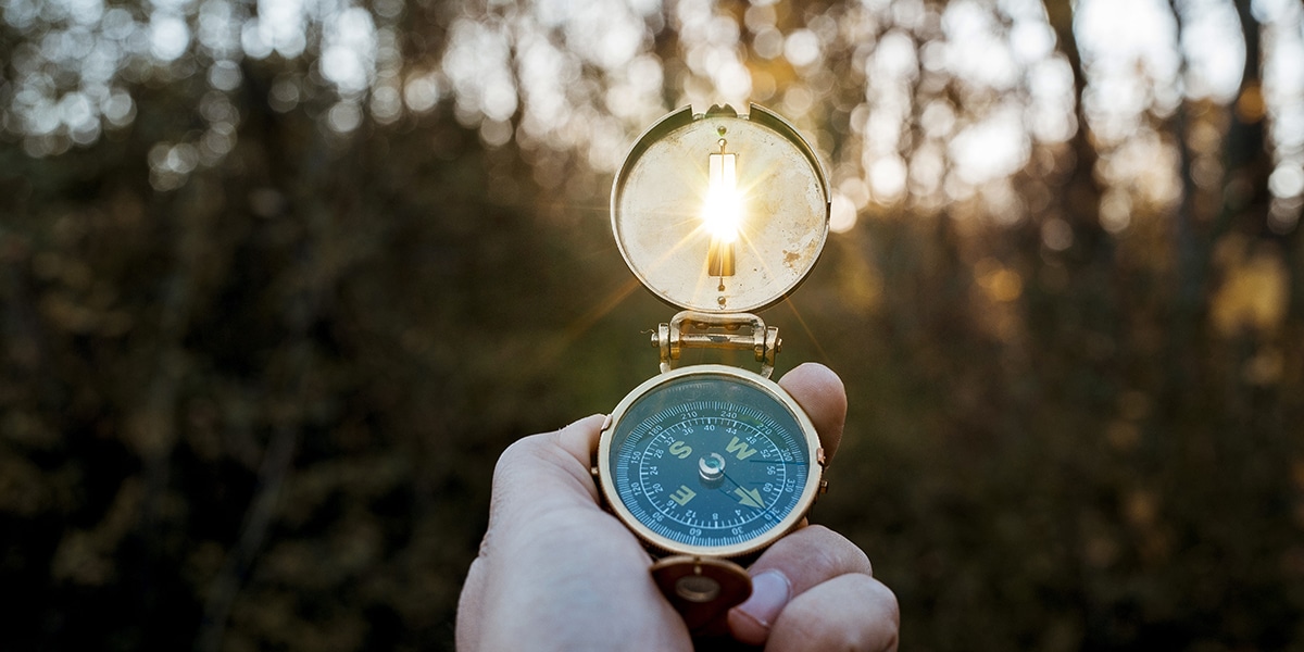 hand holding a compass showing the direction
