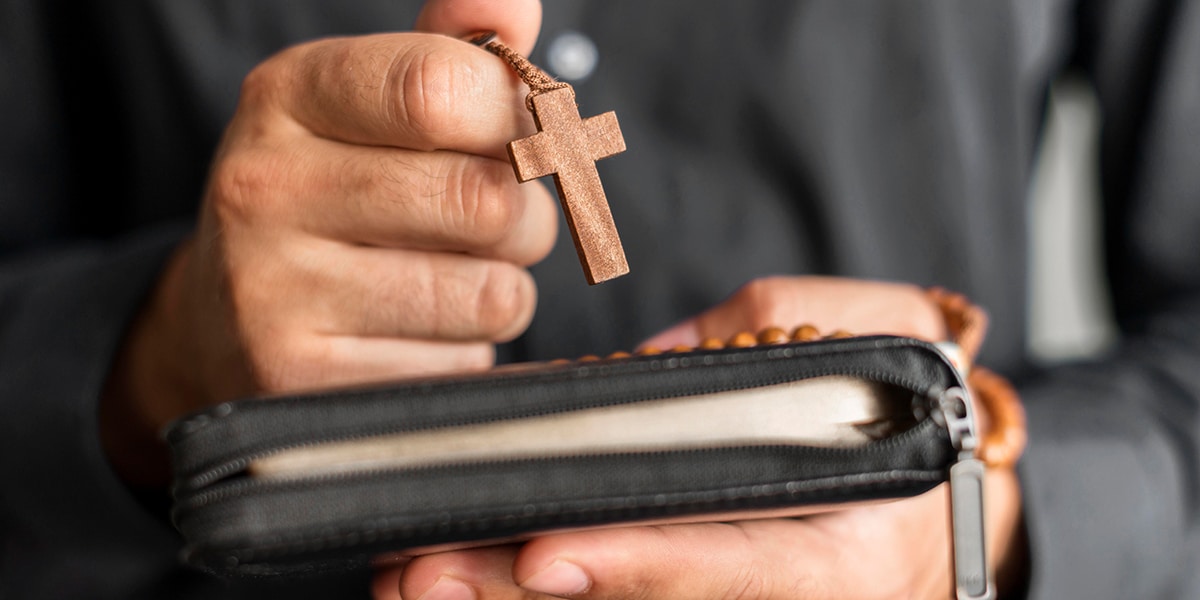 person holding a rosary and a bible