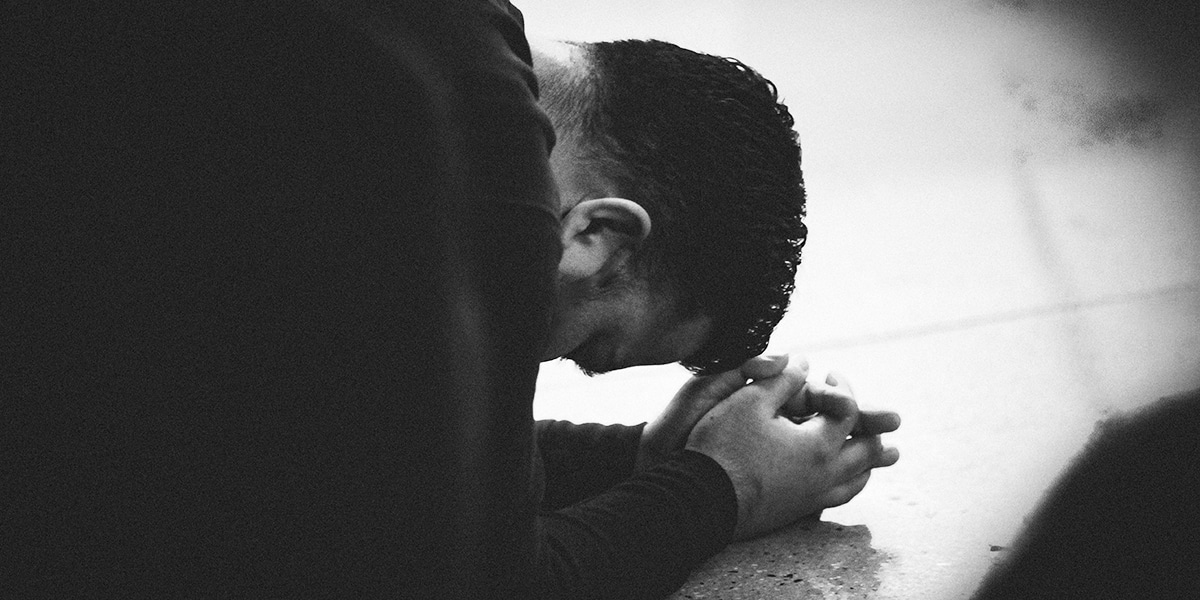 Man praying and kneeling in surrender to God
