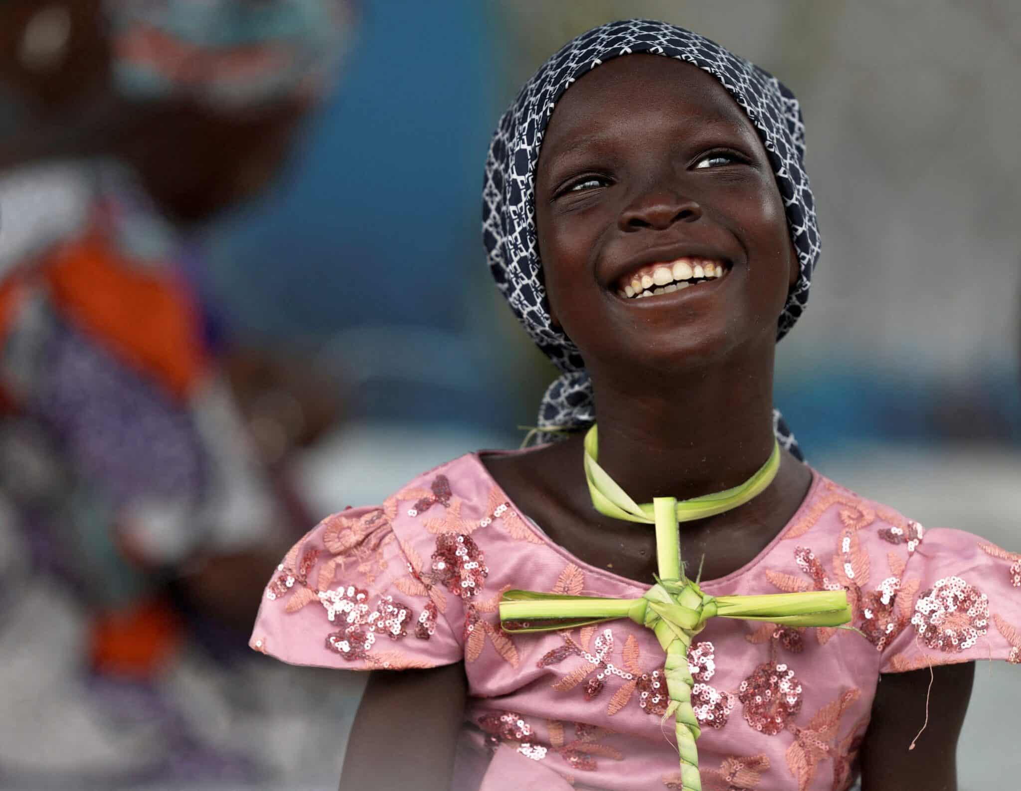 A girl smiles while holding a palm frond cross during Palm Sunday Mass at the Regina Mundi Catholic Church in Lagos, Nigeria.