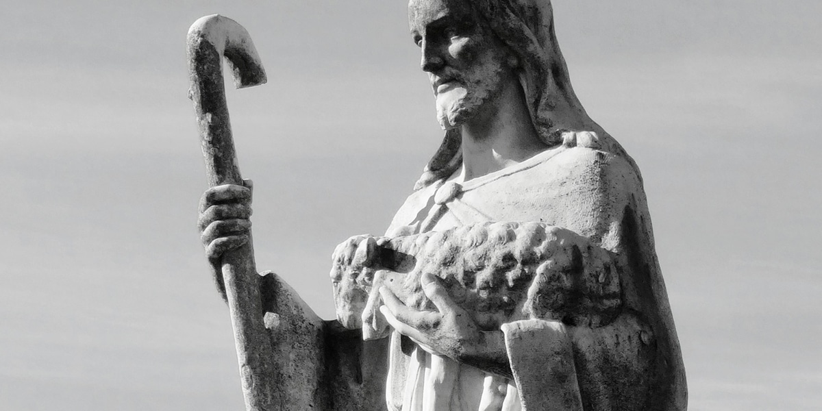 statue of Jesus as shepherd holding a staff and a lamb.