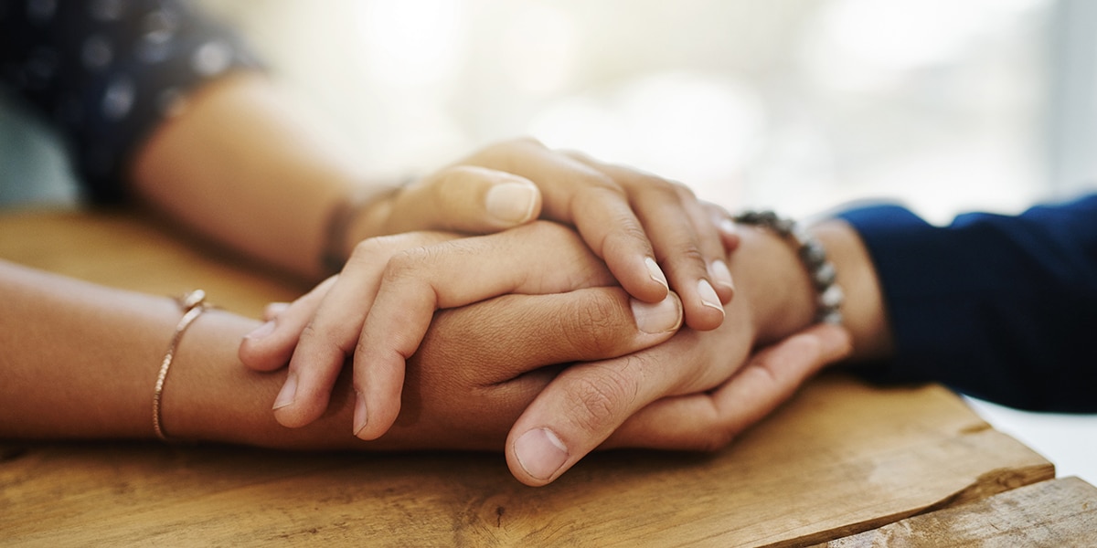 Hands holding another hand as a sign of forgiveness