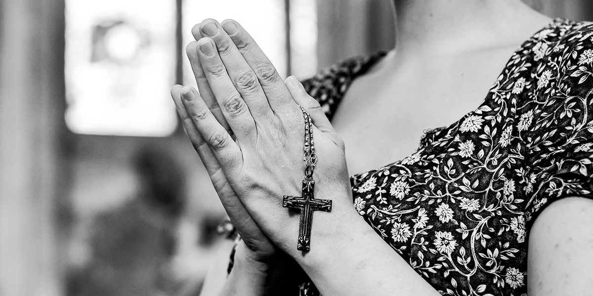 woman praying in church with a rosary