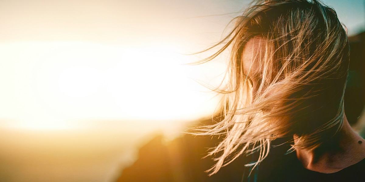 woman quietly listening, meditating with sunshine in the background